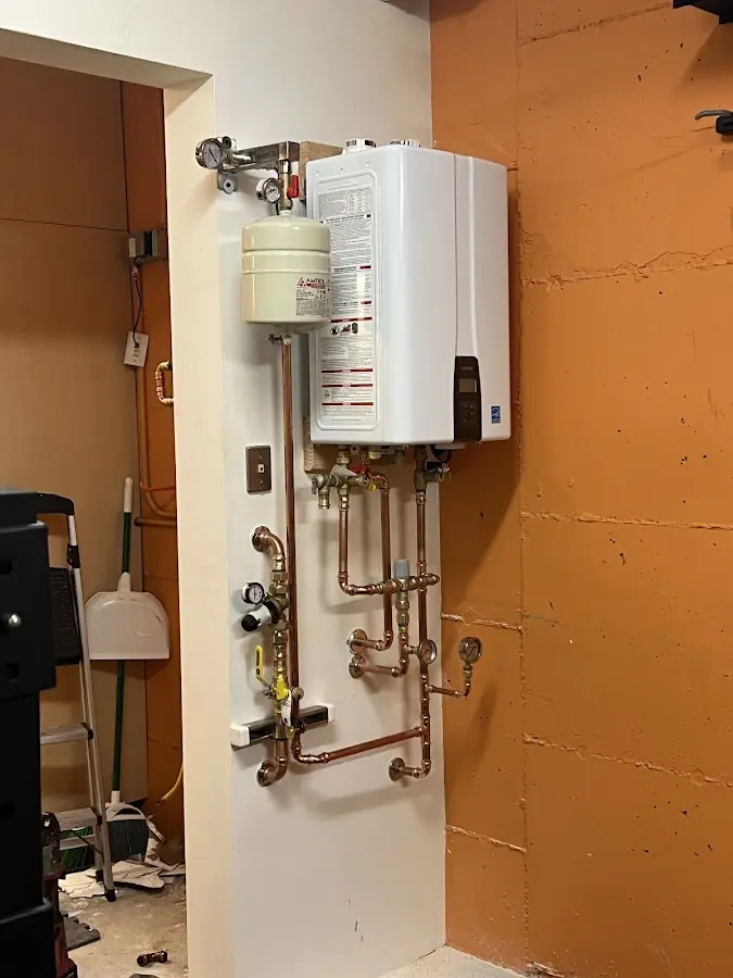 Plumbing technician inspecting water heater connections in Spring Arbor